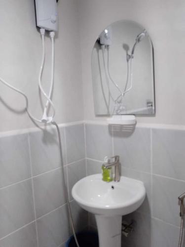 a white bathroom with a sink and a mirror at Saekyung Condominium in Basbas