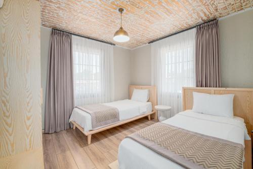 two beds in a room with two windows at Baska Urla Otel in Denizli