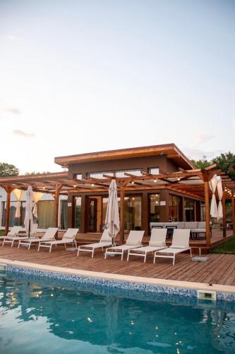 a pool with white lounge chairs and a house at Aurorae Residence in Recaş