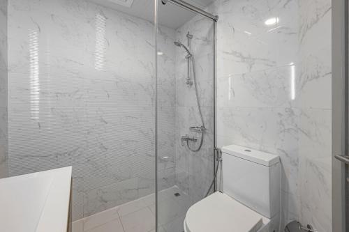 a white bathroom with a shower and a toilet at Comfortable Studio with Dubailand Vibes in Dubai