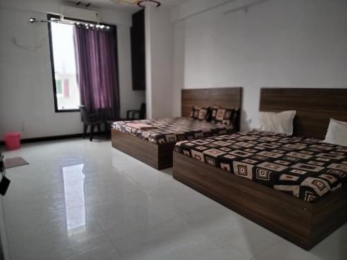 a bedroom with two beds and a window at Ashirwad Hotel in Rīngas