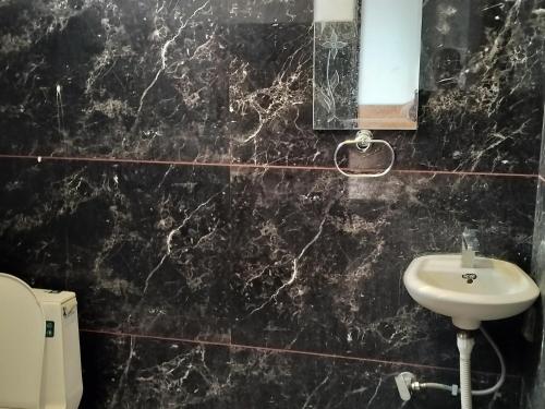 a black marble bathroom with a sink and a mirror at Ashirwad Hotel in Rīngas