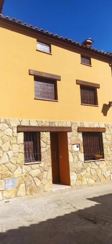a stone building with three windows and a door at Casa Misi in Candeleda