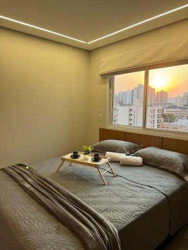 a bedroom with a bed with a table on it at Apartamento 121 - Home in Ribeirão Preto