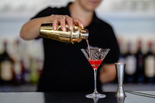 a woman pouring a red drink into a martini glass at Residence San Michele in Costermano sul Garda