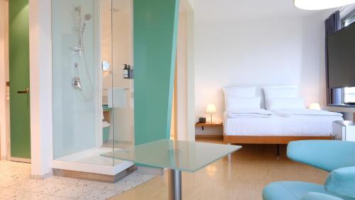 a bathroom with a glass table and a bed at FOUR Munich Neue Messe in Munich