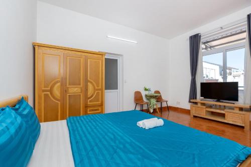 a bedroom with a blue bed and a television at Ann Homestay Vũng Tàu in Vung Tau