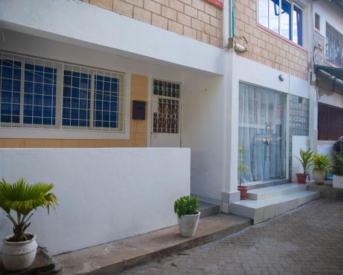 a white building with potted plants in front of it at Serena Road Villa B in Shanzu