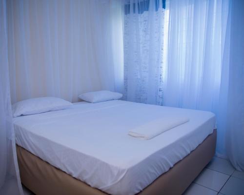 a white bedroom with a bed with white curtains at Serena Road Villa B in Shanzu