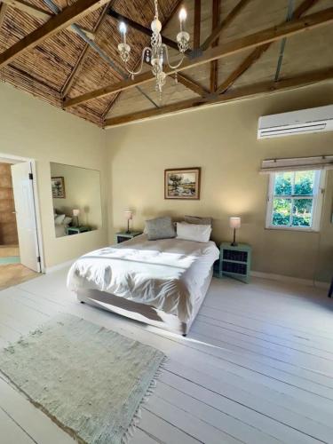 a bedroom with a large bed and a wooden ceiling at Simunye Cottage in Simondium