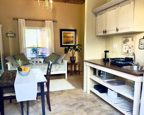 a kitchen and living room with a couch and a table at Simunye Cottage in Simondium