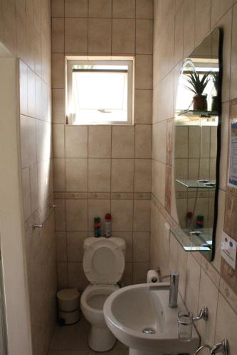 a bathroom with a toilet and a sink and a window at Esperanca Guesthouse in Windhoek