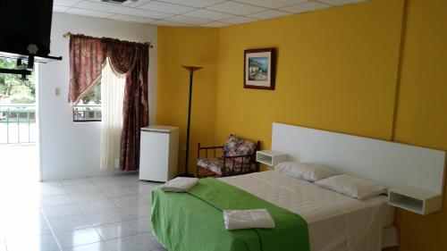 a bedroom with a bed and a chair and a window at Hotel Juan Sebastián in Atacames