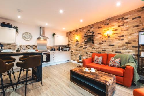 a living room with a red couch and a kitchen at Manor House Apartment in Bournemouth
