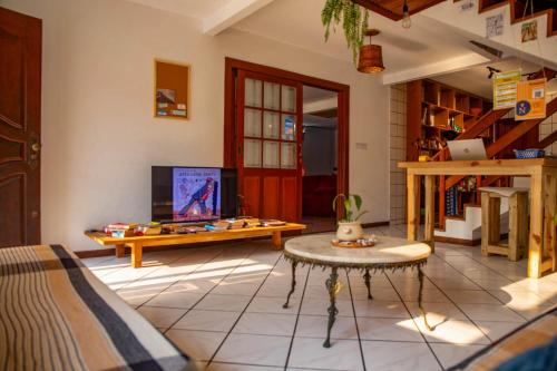 a living room with a tv and a table at Nômades Beach - Adventure Hostels in Florianópolis