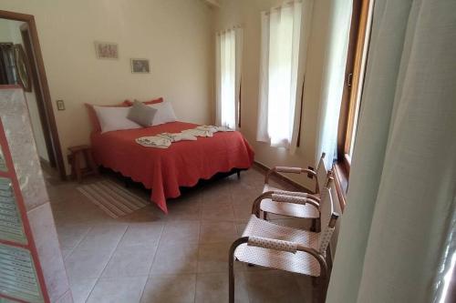 a bedroom with a bed with a red blanket at Vale do Sol Chalé in Santa Luísa de Baixo