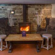 a fireplace in a room with a table and two stools at The Crown Inn in Towcester