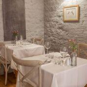 a restaurant with two tables with white table cloth at The Crown Inn in Towcester