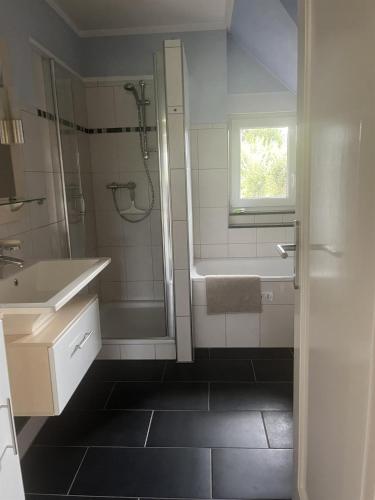 a white bathroom with a shower and a sink at Ferienwohnung Olendorp in Hermannsburg