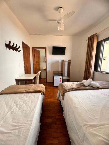 a hotel room with two beds and a table at Hotel Real Cruzilia in Cruzília