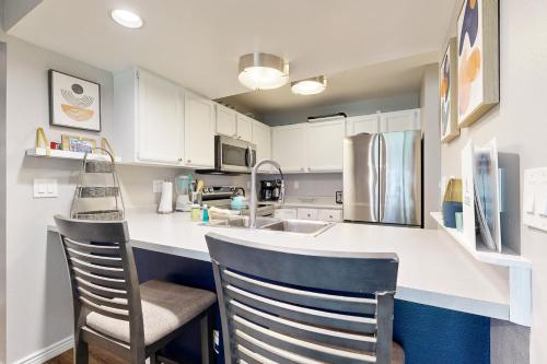 a kitchen with white cabinets and a counter with chairs at Eagle River's Charmer in Edwards