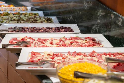 a buffet filled with different types of food on trays at Hotel Mondolé - Azzurro Club in Prato Nevoso
