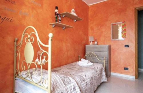 a bedroom with a bed and an orange wall at Green House in Monopoli