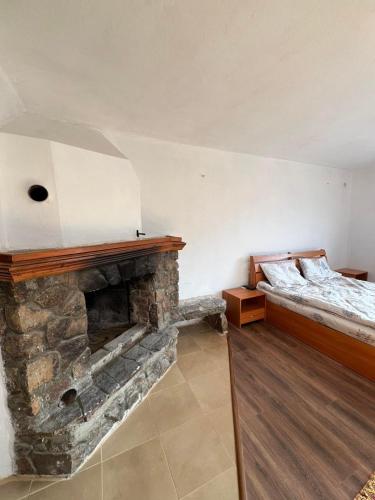 a bedroom with a stone fireplace and a bed at Чемерникъ in Gabrovnitsa
