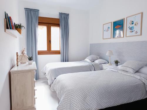 a bedroom with three beds and a window at Muy acogedor, a 5 min a pie del centro, Cama 1'60, Wifi y Netflix in San Vicente de la Barquera