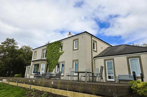 a house with a table and chairs in front of it at Ard Veich Estate - Panoramic Highland Sea Views with private beach and woodland in Port Appin