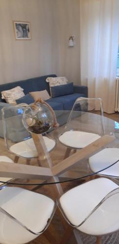 une table en verre avec quatre chaises blanches et un canapé bleu dans l'établissement Maison Cosy Mulhouse, à Mulhouse