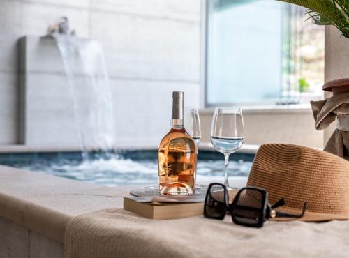 a bottle of wine and glasses on a table next to a swimming pool at Luxury Private Spa Apartment with Heated Pool & Sauna and Sea View in Cavtat