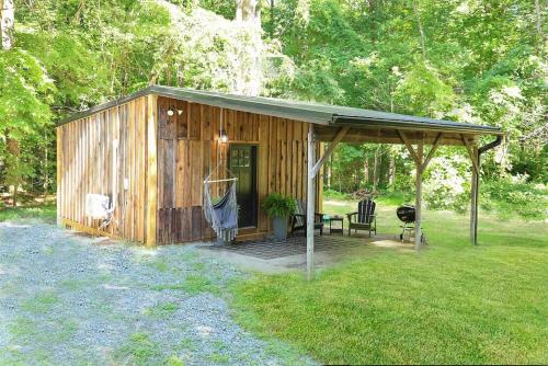 a wooden shed with a porch in the grass at Tiny Tarheel Cozy Retreat Near UNC Tiny House in Chapel Hill
