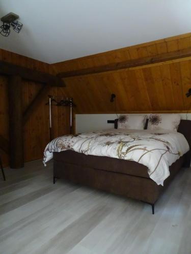 a bedroom with a large bed with a wooden ceiling at B&B Aan de Vaart in Bovensmilde