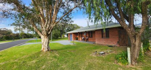 a red brick house with a tree in the yard at Abbey Beach Shack in Busselton