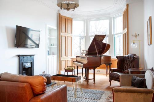 a woman playing a piano in a living room at Oakshaw Apartment in Paisley