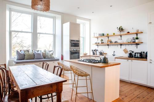 a kitchen with white cabinets and a wooden table at Oakshaw Apartment in Paisley