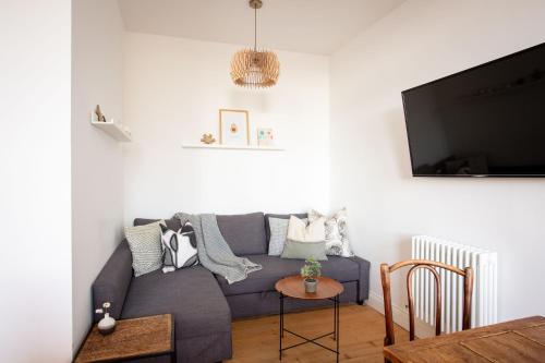 a living room with a blue couch and a flat screen tv at Oakshaw Apartment in Paisley