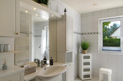 a white bathroom with a sink and a mirror at Haus Scheve in Rhauderfehn
