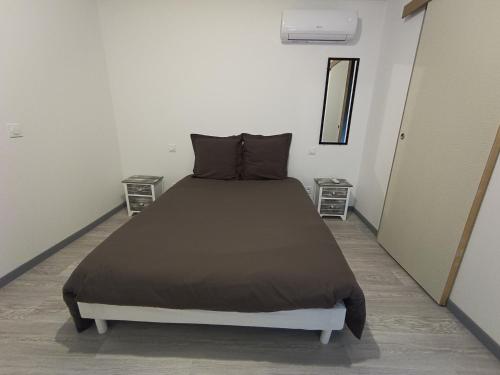 Ce lit se trouve dans un dortoir blanc doté de 2 tables de nuit. dans l'établissement Appart complet 2 chambres calme facture et repas possibles, à Beausemblant