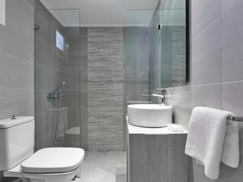 a white bathroom with a toilet and a sink at Kinetta Beach Resort and Spa in Kineta