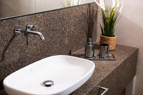 a white sink in a bathroom with plants on a counter at Olympic Star Beach Hotel in Nei Poroi
