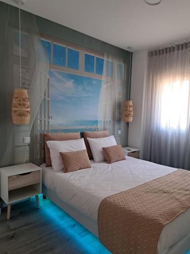 a bedroom with a large bed with a large window at Condomínio do Cabedelo in Figueira da Foz