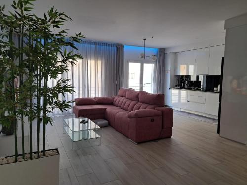 a living room with a red couch and a kitchen at Condomínio do Cabedelo in Figueira da Foz