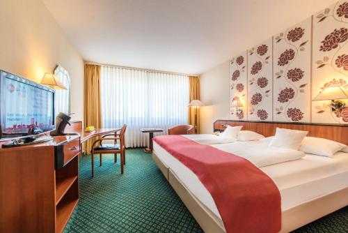 a hotel room with a bed and a desk and a television at Best Western Plus Delta Park Hotel in Mannheim