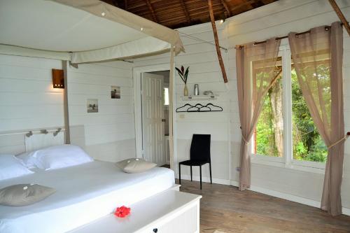 ein Schlafzimmer mit einem Bett, einem Stuhl und einem Fenster in der Unterkunft Nathylodge in Bocas del Toro