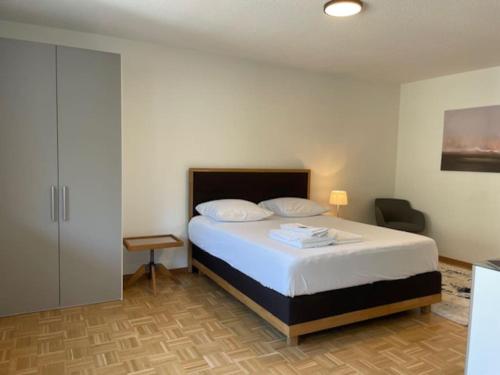 ein Schlafzimmer mit einem Bett und einem Stuhl darin in der Unterkunft Bright and practical Studio - Art 16 in Zürich