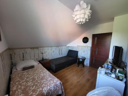 a bedroom with a bed and a couch and a chandelier at Willa Rudnik in Grudziądz