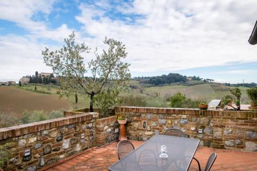 a patio with a table and chairs and a stone wall at Antica Fonte Residenza di Siena in Siena