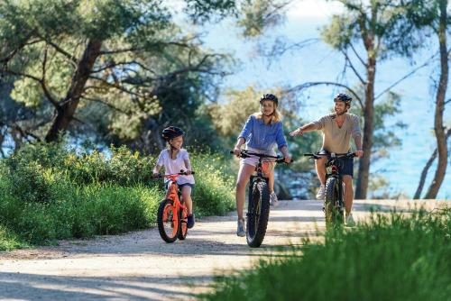 two adults and a child riding bikes down a trail at Sani Beach in Sani Beach